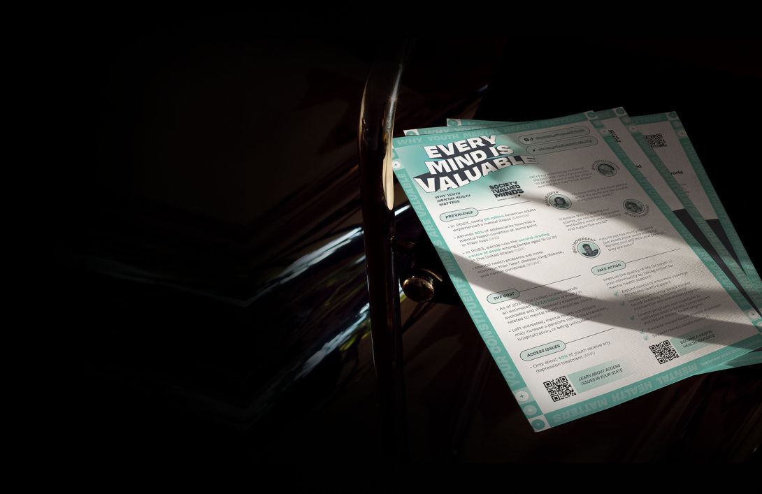 Background image; a printed Society of Valued Minds "Mental Health Multi-Tool" resource sits in the sunlight.